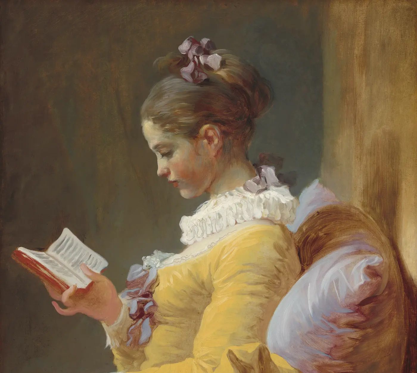 A girl in a yellow dress absorbed in a small book.